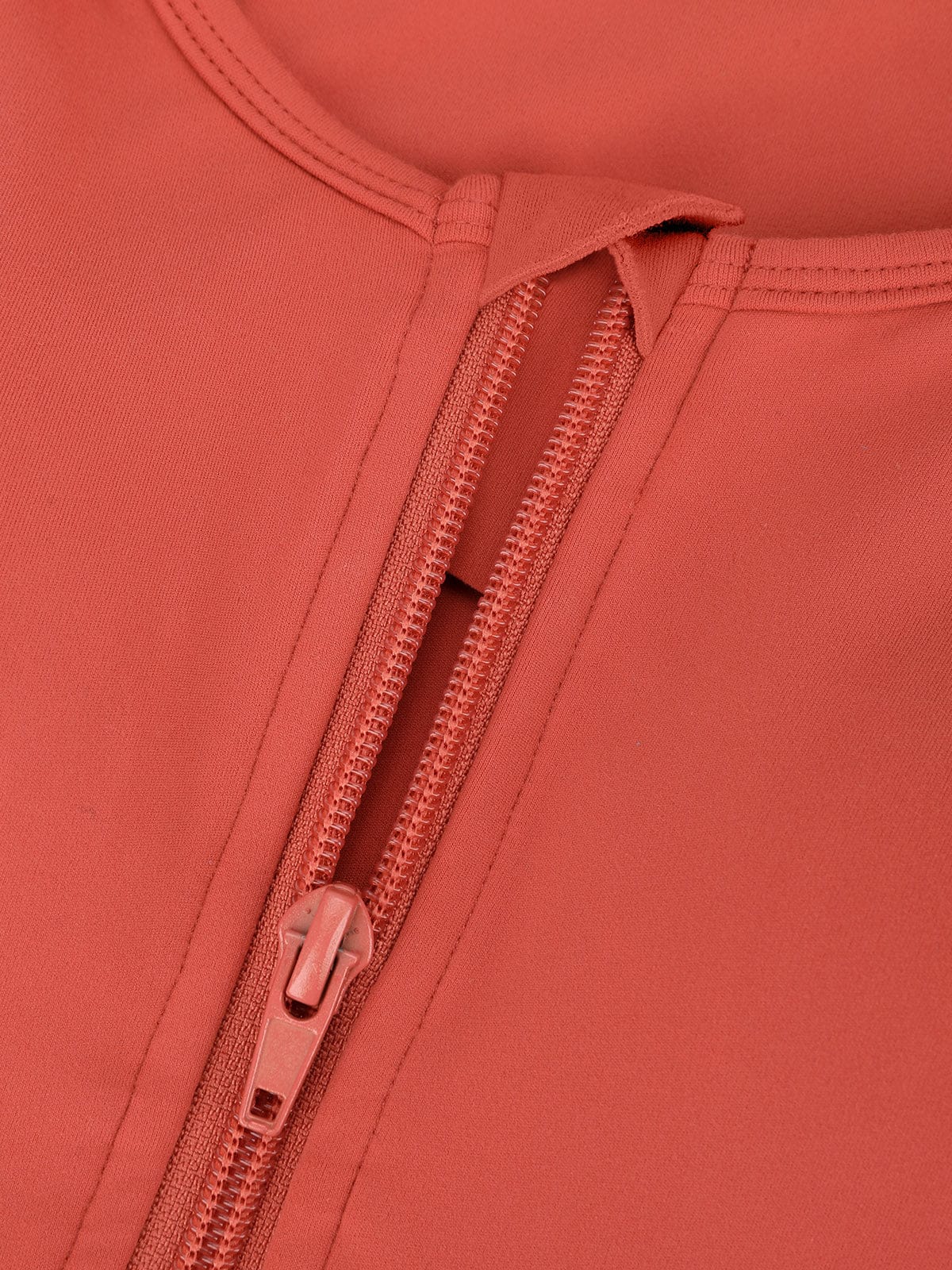 Close-up detail of the durable front zipper and protective fabric backing on Vractive Mineral Red sports bra