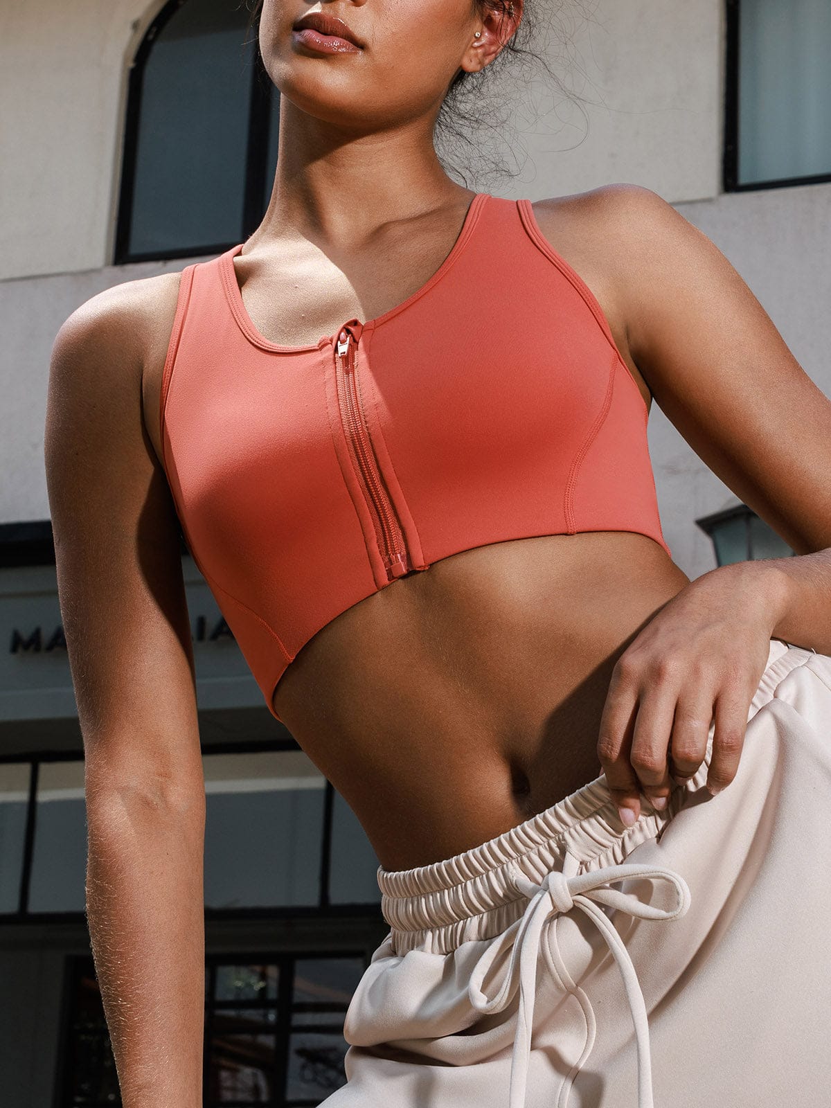 Lifestyle shot of model wearing Vractive Mineral Red front-zip sports bra in an active fitness setting