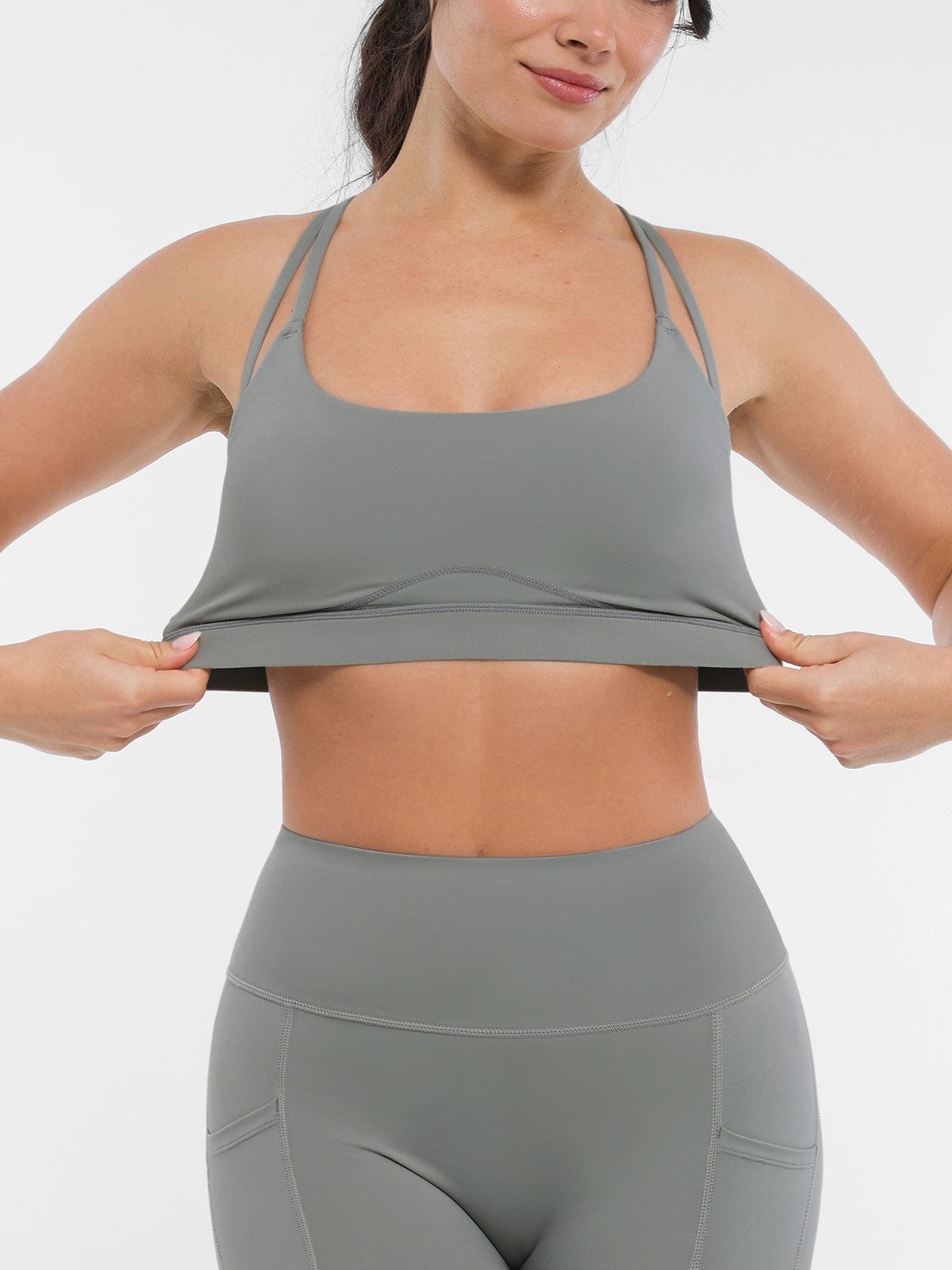 Vractive Neutral Gray sports bra underbust band being stretched to demonstrate high elasticity and durable shape retention.